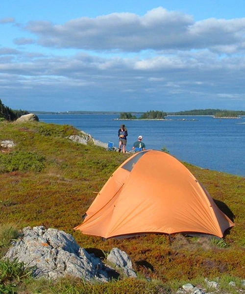 This is an image of two people enjoying the lakeview with a tent set up nearby.